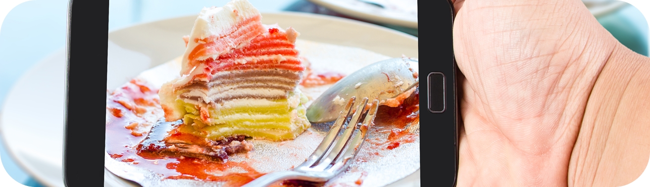 Man hand hold touch screen smart phone in pastry and cake shop.