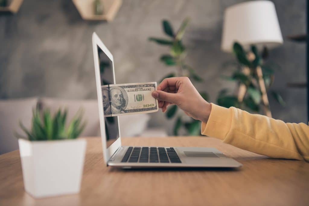 woman pulling money out of her laptop screen illustrating how a website can make you money