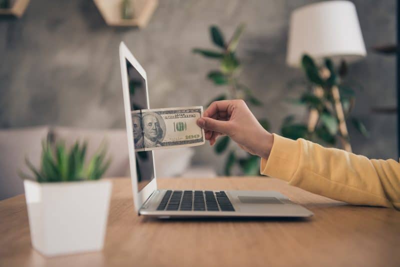 woman pulling money out of her laptop screen illustrating how a website can make you money