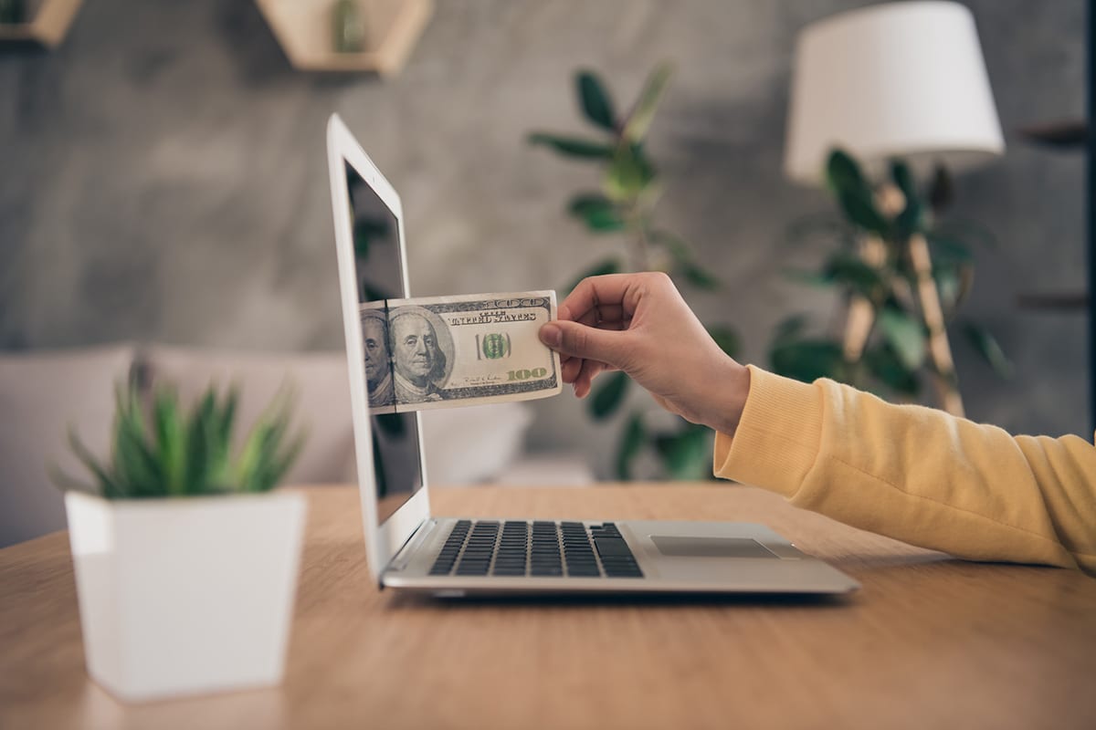 woman pulling money out of her laptop screen illustrating how a website can make you money