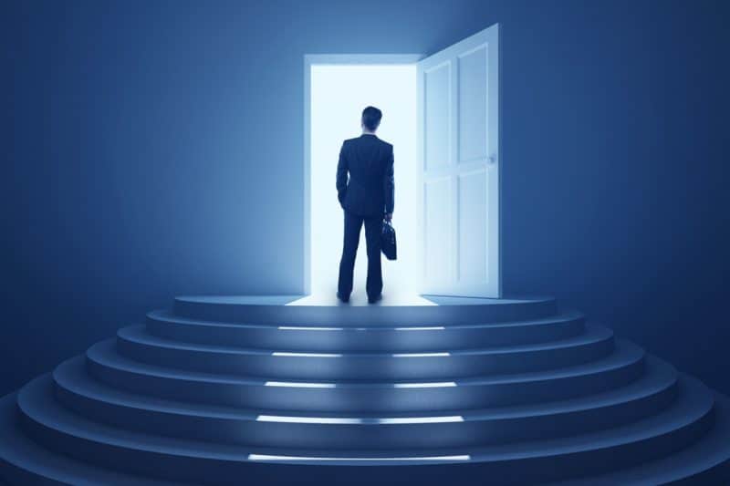 a business owner standing at a doorway with light shining through it illustrating a doorway to success